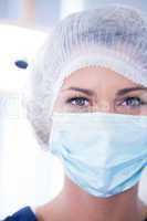 Dentist in surgical mask and cap looking at camera