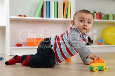 Baby beim Spielen mit Spielzeugauto im Kinderzimmer