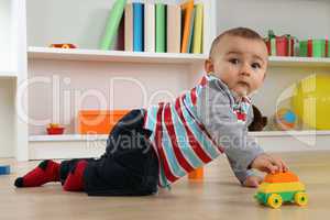 Baby beim Spielen mit Spielzeugauto im Kinderzimmer