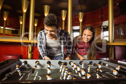 Smiling friends playing table football together