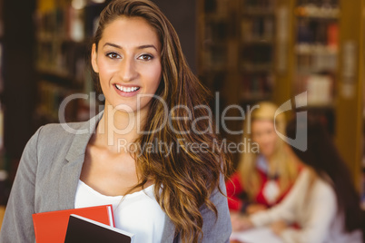 Portrait of a pretty brunette student holding books