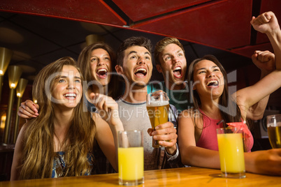 Happy friends drinking beer and cheering together