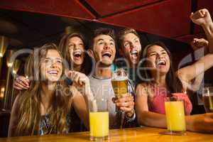 Happy friends drinking beer and cheering together