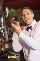 Handsome barman smiling at camera making a cocktail