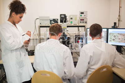 Biochemistry students using large microscope and computer