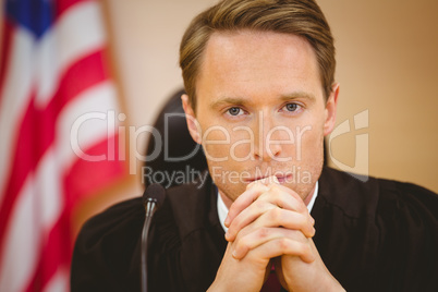 Unsmiling judge with american flag behind him