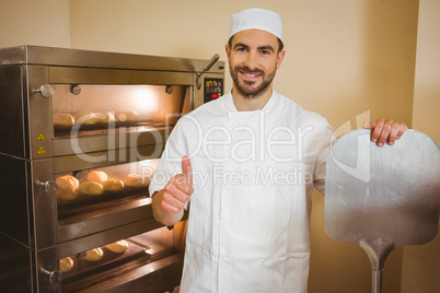 Baker smiling at camera beside oven