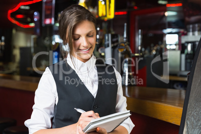 Happy barmaid writing in notepad