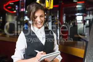 Happy barmaid writing in notepad