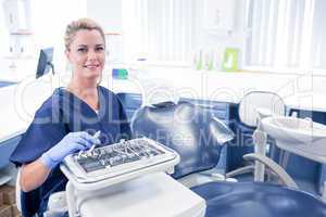 Dentist sitting with tray of tools smiling at camera