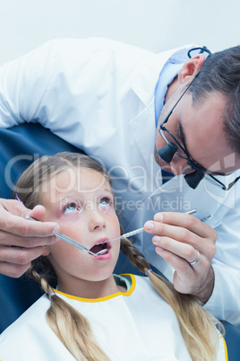 Male dentist examining girls teeth