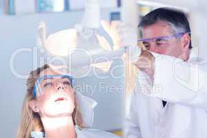 Dentist examining a patients teeth in chair under bright light