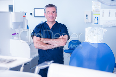 Dentist in blue scrubs smiling at camera