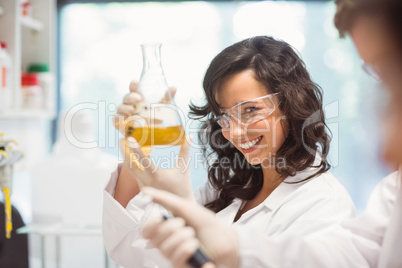 Pretty science student smiling and holding beaker