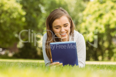 Smiling university student lying and using tablet pc Smiling university student lying and using tablet pc