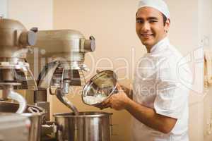 Baker pouring flour into large mixer