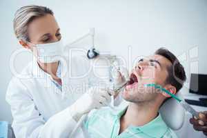 Female dentist examining mans teeth