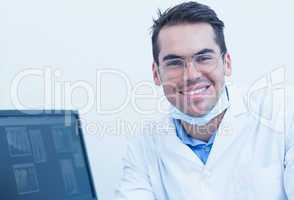 Smiling male dentist with computer monitor
