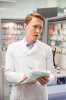 Focused pharmacist writing on clipboard