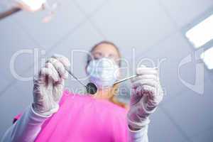 Dentist in surgical mask holding tools over patient