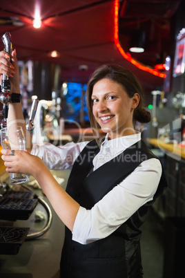 Happy barmaid pulling a pint of beer