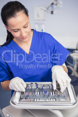 Smiling dentist picking up a tool on the tray