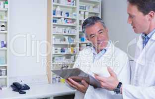 Pharmacists holding medication and writing a prescription