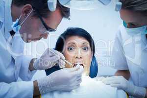 Dentist with assistant examining womans teeth