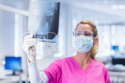 Dentist in mask and protective glasses holding an x-ray