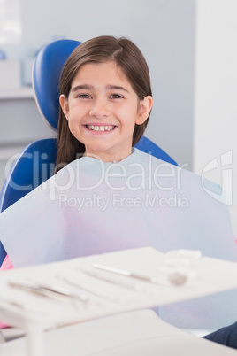 Smiling young patient sitting in dentists chair