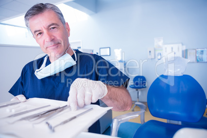 Dentist picking up tool and smiling at camera