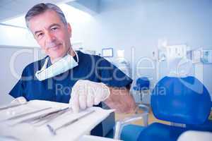 Dentist picking up tool and smiling at camera