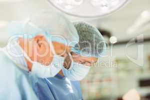 Older surgeon teaching new surgeon how to operate