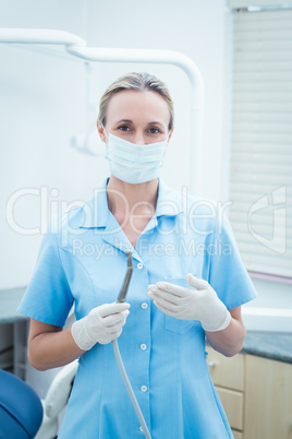 Female dentist in surgical mask holding dental tool