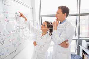 Science student and lecturer looking at whiteboard