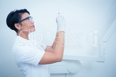 Female dentist in surgical mask holding injection