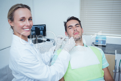 Female dentist examining mans teeth