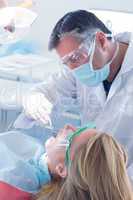 Dentist examining a patients teeth in the dentists chair