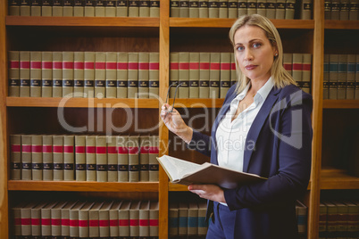 Focused librarian holding book and reading glasses