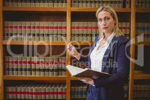 Focused librarian holding book and reading glasses