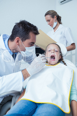 Male dentist examining girls teeth