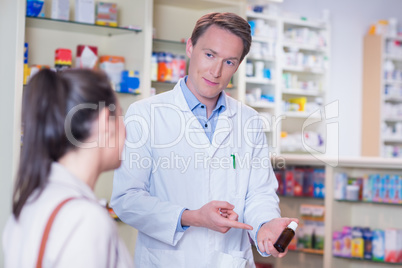 Pharmacist pointing a flask of pills in front of a customer