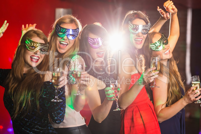 Friends in masquerade masks drinking champagne