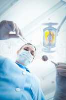 Female dentist in surgical mask holding dental tools