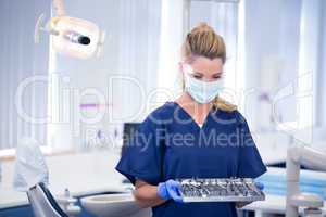 Dentist in mask holding tray of tools