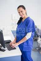 Smiling dentist typing on keyboard