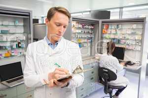 Focused pharmacist writing on clipboard