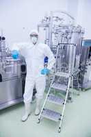 Scientist in protective suit leaning against machine