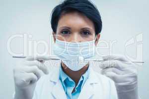 Female dentist in surgical mask holding dental tools