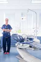 Dentist in blue scrubs standing with arms crossed